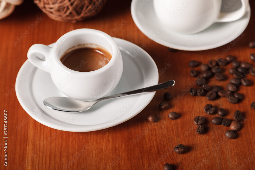 White espresso coffee Cup, coffee beans and milk jug on wooden background. Concept of coffee breaks and serving coffee