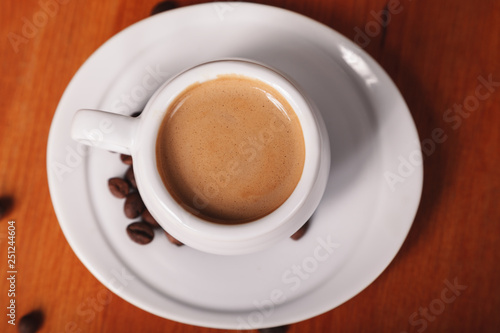 White coffee Cup with thick milk foam, close-up top view on wooden table. Concept of coffee break and serving coffee