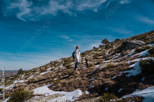 Young backpacker enjoying a sunny winter day in the mountains. Breathing fresh air  relaxed and carefree. Some snow all around. Amazing view. Lifestyle.