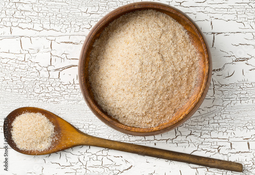 Heap of psyllium husk also called isabgol in wooden bowl and spoon on white table background flat lay from above photo