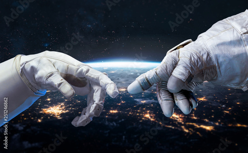 Astronaut and robot hands in the space. Earth planet on the background. Communication and technology. Cities lights. Elements of this image furnished by NASA photo