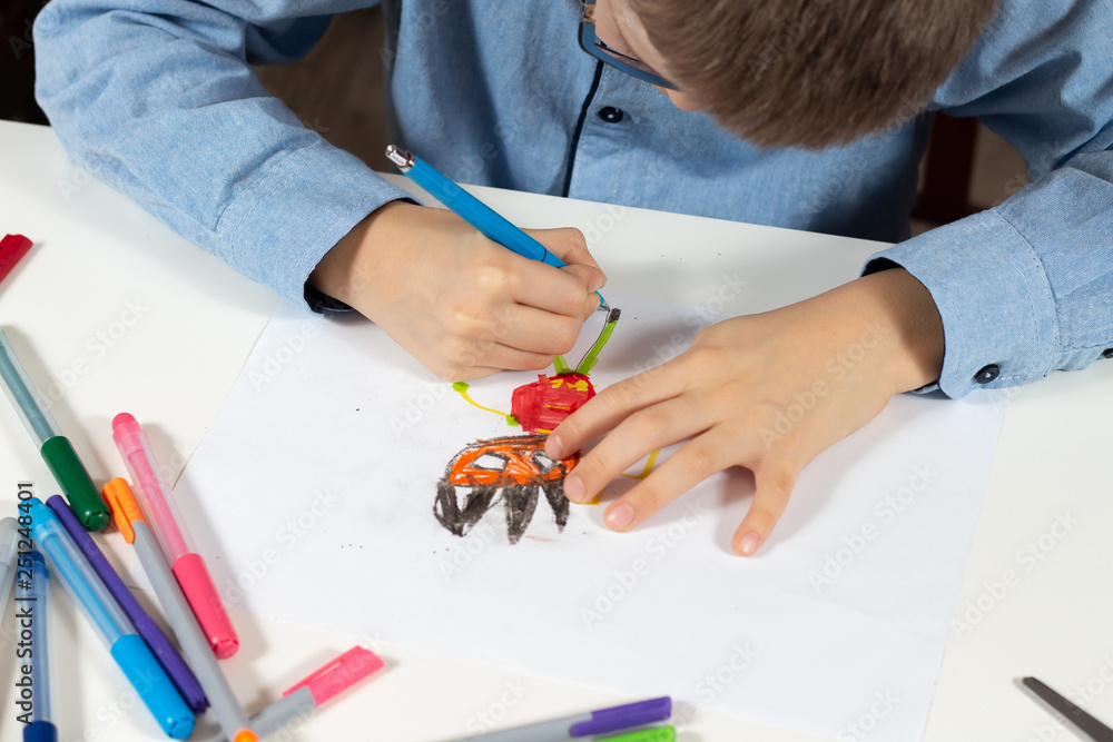 Dłonie dziecka trzymają długopis i rysują wymyśloną postać na białej kartce papieru. - obrazy, fototapety, plakaty 