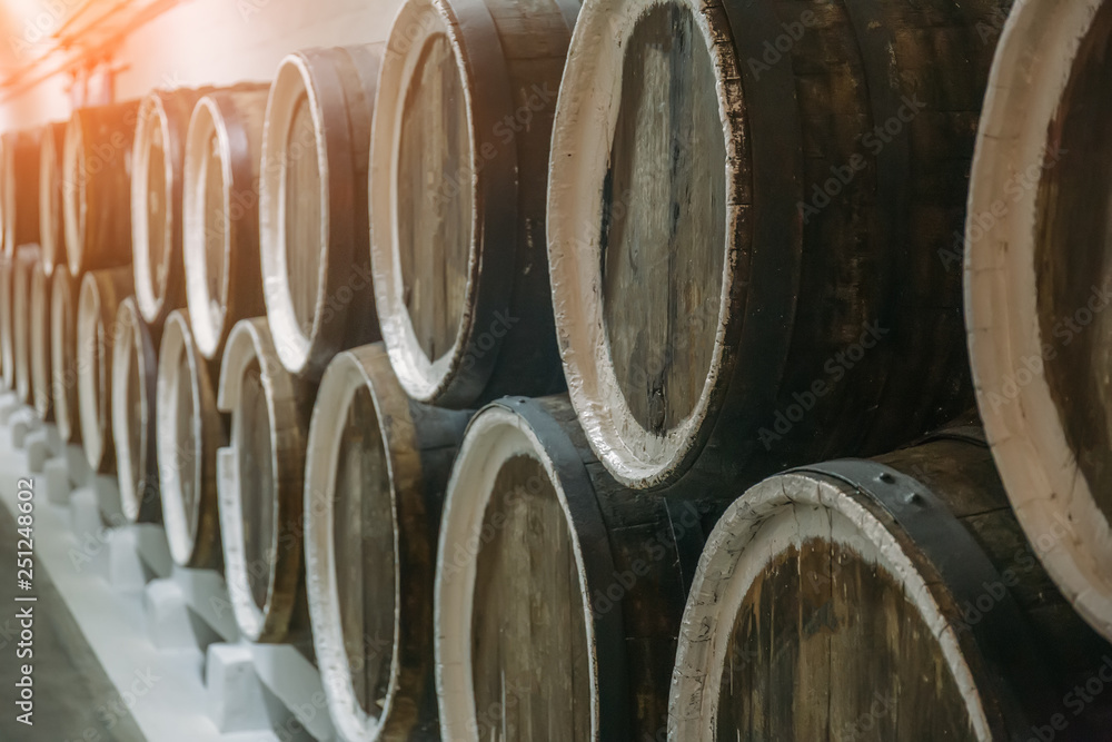 Wine cellar and rows of barrels with liquor or alcohol, closeup