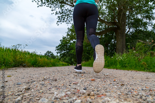 eine sportliche Frau joggt einen weg entlang