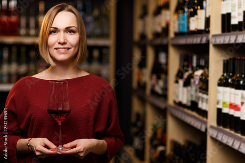 Picture of woman with glass in hands at store with wine