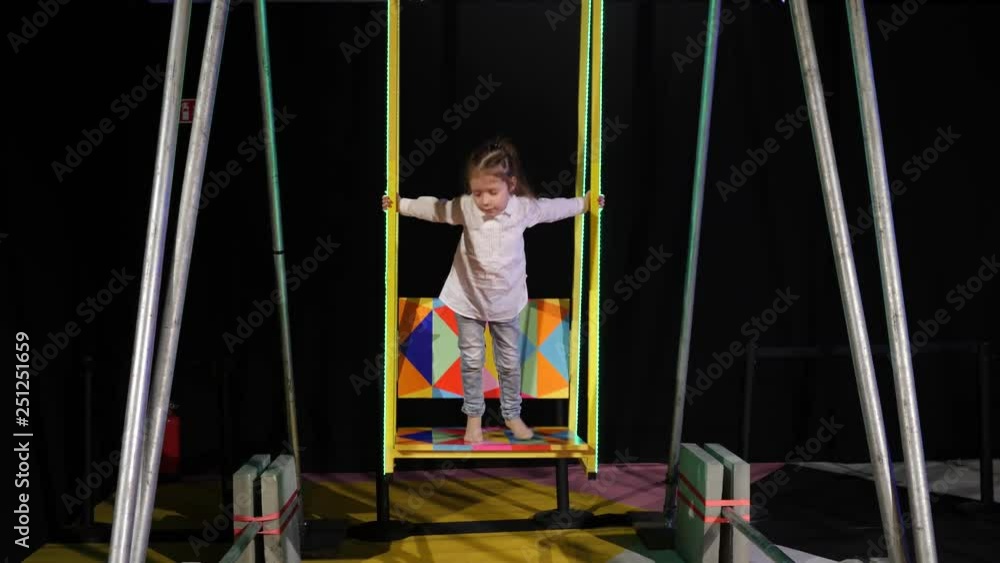Cute little girl stay on a swing swaying slowly enjoying the play Cute little girl stay on a swing swaying slowly enjoying the play