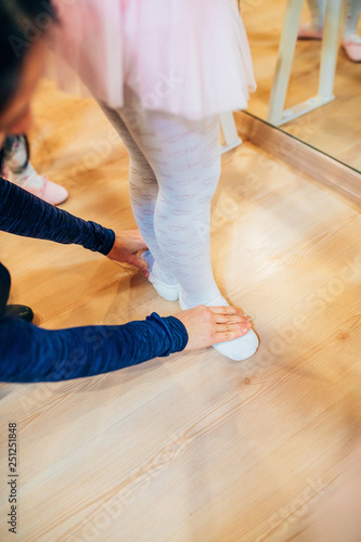 Young ballet dancer warming up in front of mirror. Child ballerina leg or feets in ballet position.