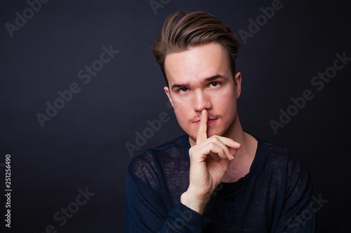 Young man showing silence gesture