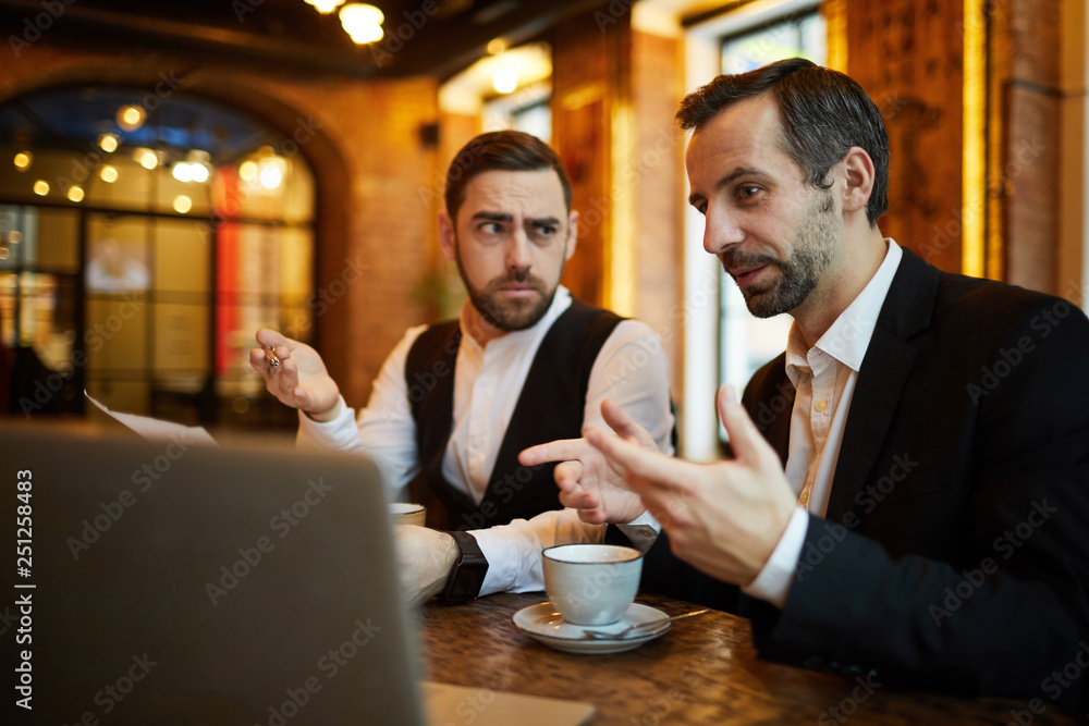 Portrait of two successful business people working in cafe and using laptop, copy space