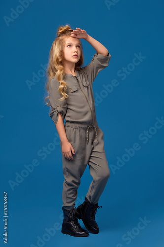 Little girl in a fashionable clothes on blue background