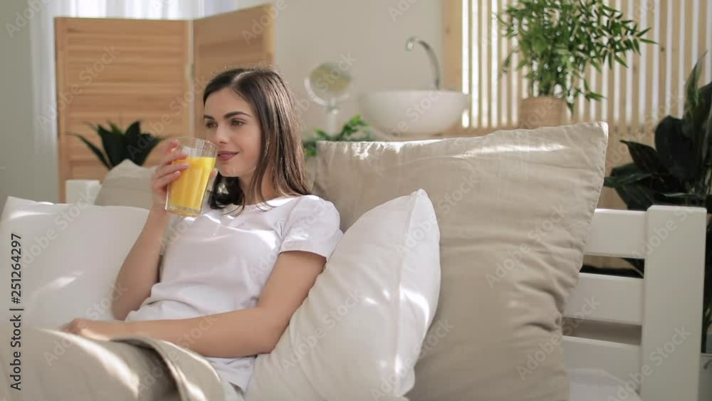 Attractive woman sitting in bed and drinking orange juice Attractive woman sitting in bed and drinking orange juice