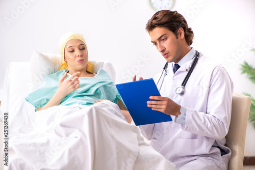 Young handsome doctor visiting female oncology patient  photo