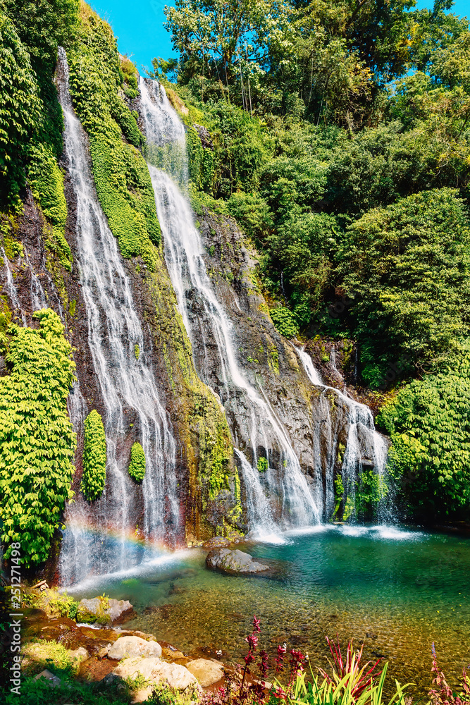 Waterfall with blue crystal water and rainbow in tropical island. Bali, Indonesia