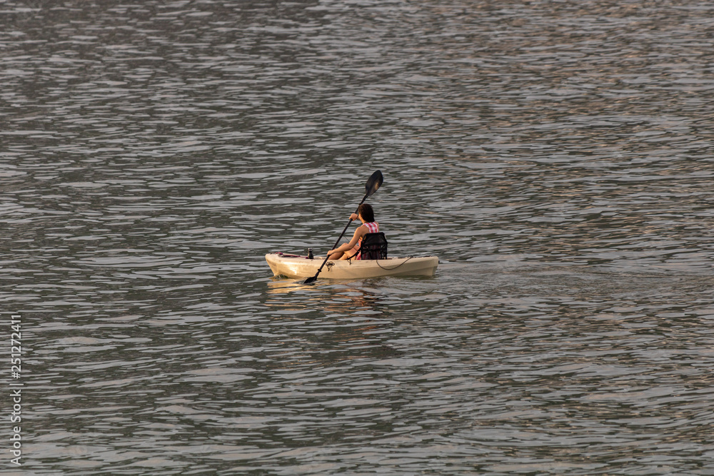 Perfect day for kayaking. Beautiful young woman paddling while sitting in kayak