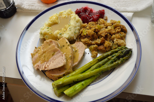 turkey dinner with gravy stuffing, mashed potatoes, cranberry sauce, and asparagus