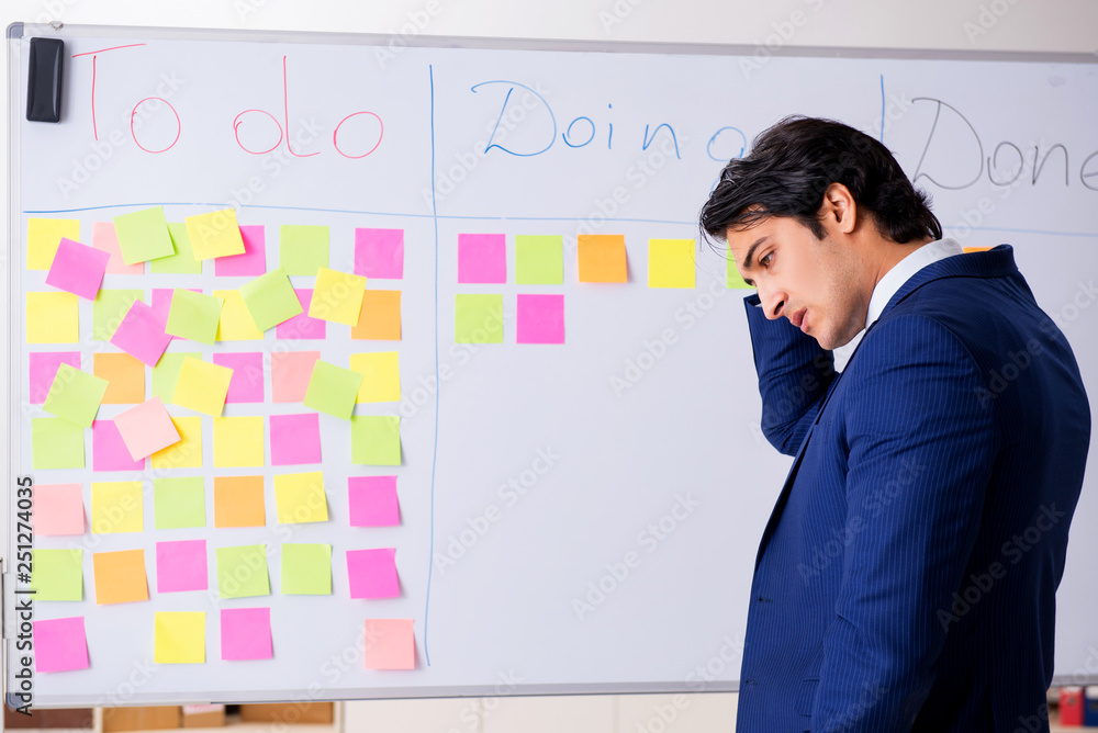 Young handsome employee in front of whiteboard with to-do list Young handsome employee in front of whiteboard with to-do list