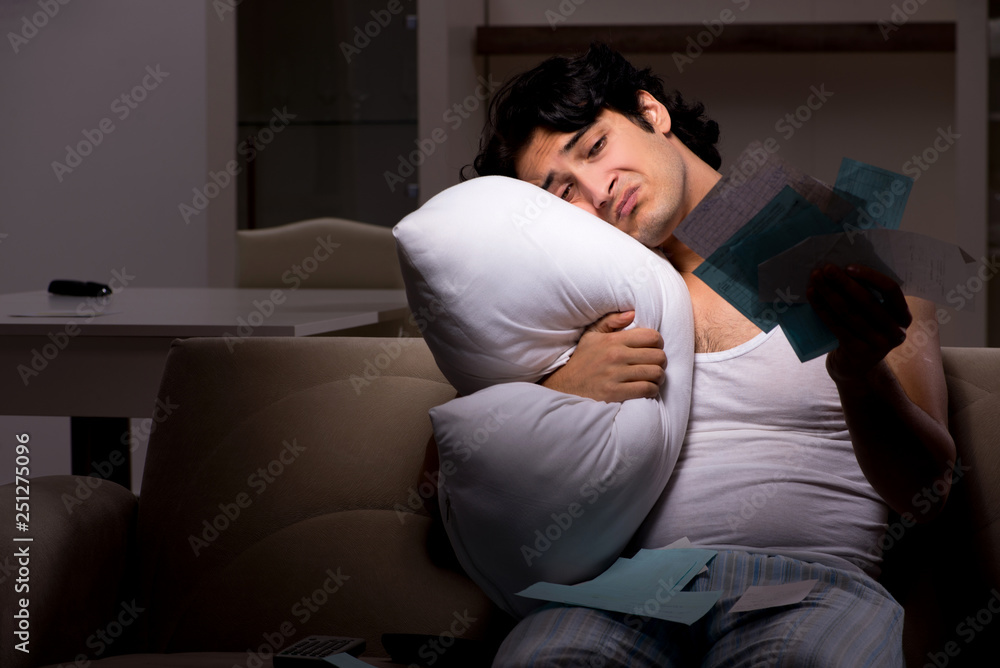 Fototapeta premium Young man calculating expences night at home