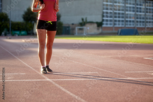 one young woman, unrecognizable person, wearing fitness clothes, walking on a sports court. On a track and field, running tracks. © HD92
