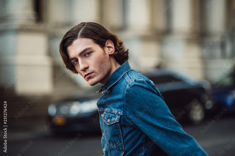 Fototapeta premium Handsome young adult man on city street wearing casual denim jeans shirt
