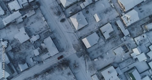 (original 4k file)  SUV shot from a drone moves among the snow-covered roofs of private houses