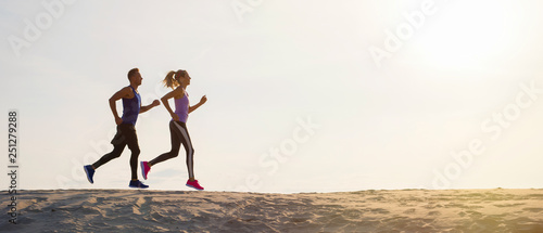 Silhouettes of man and woman running at sunset photo