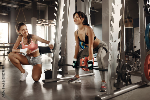 Sports woman exercising in gym with personal trainer. Workout