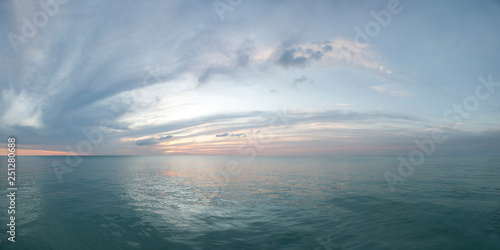Colorful seascape. Twilight sunset over the sea with colorful clouds. Panorama of cloudy sky and aqua water © Kimo