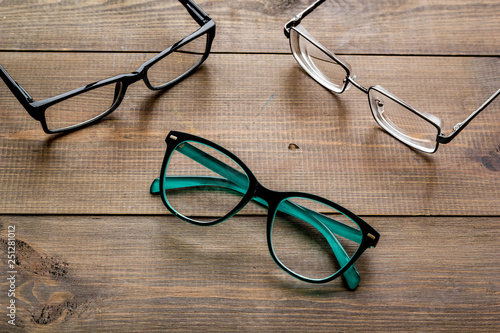 Accessories for eyes. Glasses with transparent lenses and different frames on dark wooden background