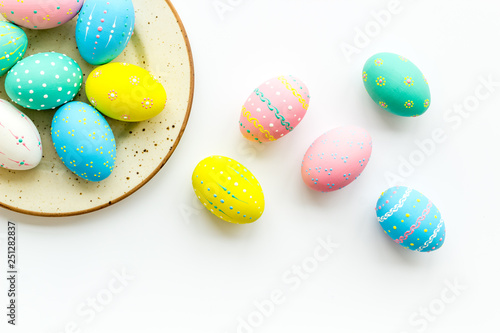 Festive Easter table. Colorful Easter eggs on plate on white background top view