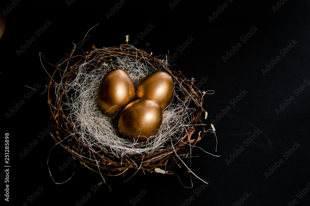 Fototapeta premium Golden Easter Eggs in birds Nest on black background. Easter Holiday concept abstract background copyspace top view several objects.