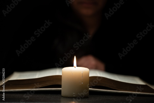 Person Reading Bible by Candle Light
