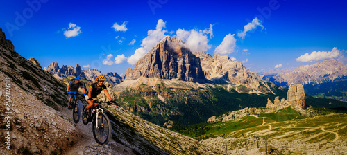Cycling woman and man riding on bikes in Dolomites mountains landscape. Couple cycling MTB enduro trail track. Outdoor sport activity.