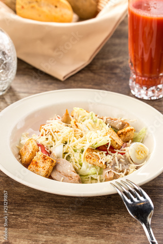 Healthy Grilled Chicken Caesar Salad with parmesan Cheese and Croutons on wooden table