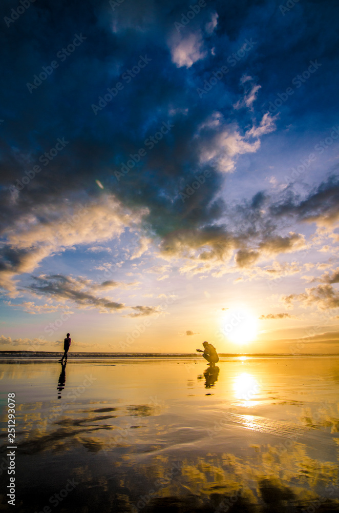 Two peoples taking a photo while Sunset at Double Six Beach, Legian, Seminyak, Kuta, Bali, Indonesia
