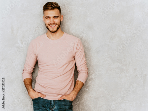 Portrait of handsome smiling hipster lumbersexual businessman model wearing casual summer pink clothes. Fashion stylish man posing against gray wall photo