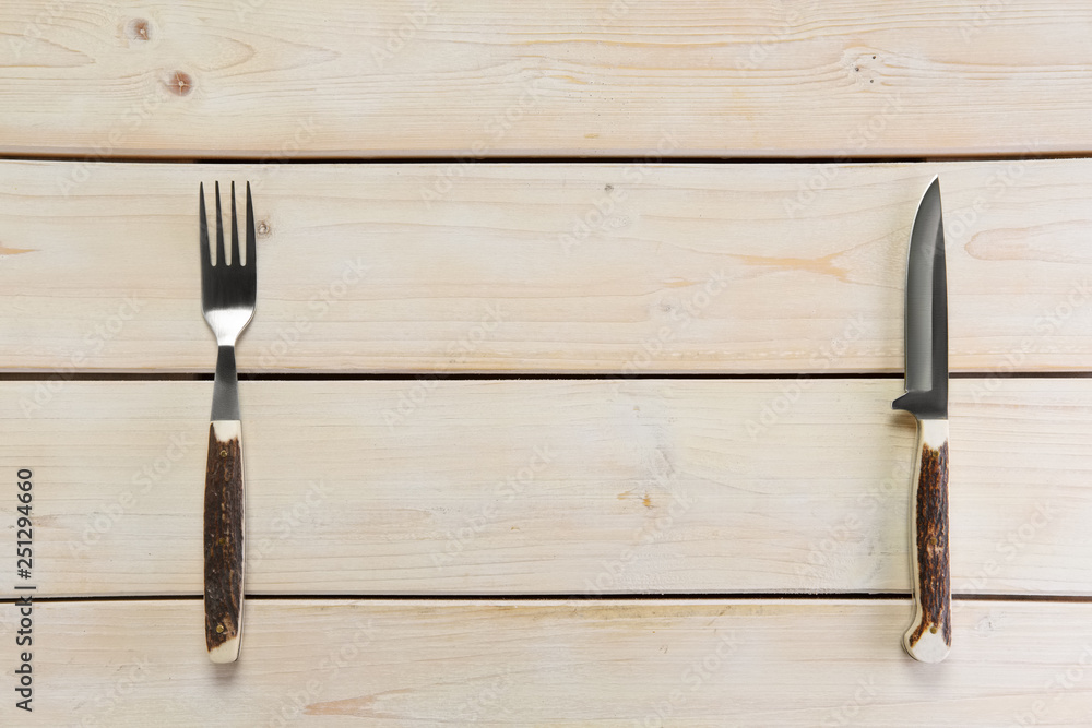Overhead view of tourist knife and fork with horn handle on empty wooden table Overhead view of tourist knife and fork with horn handle on empty wooden table