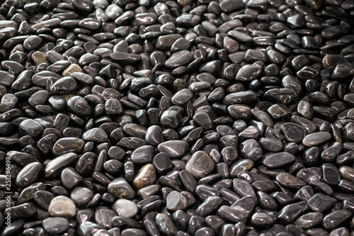Background texture of big waterworn black pebbles or stones for use in decor and garden landscaping, close up view from above, selective focus photo