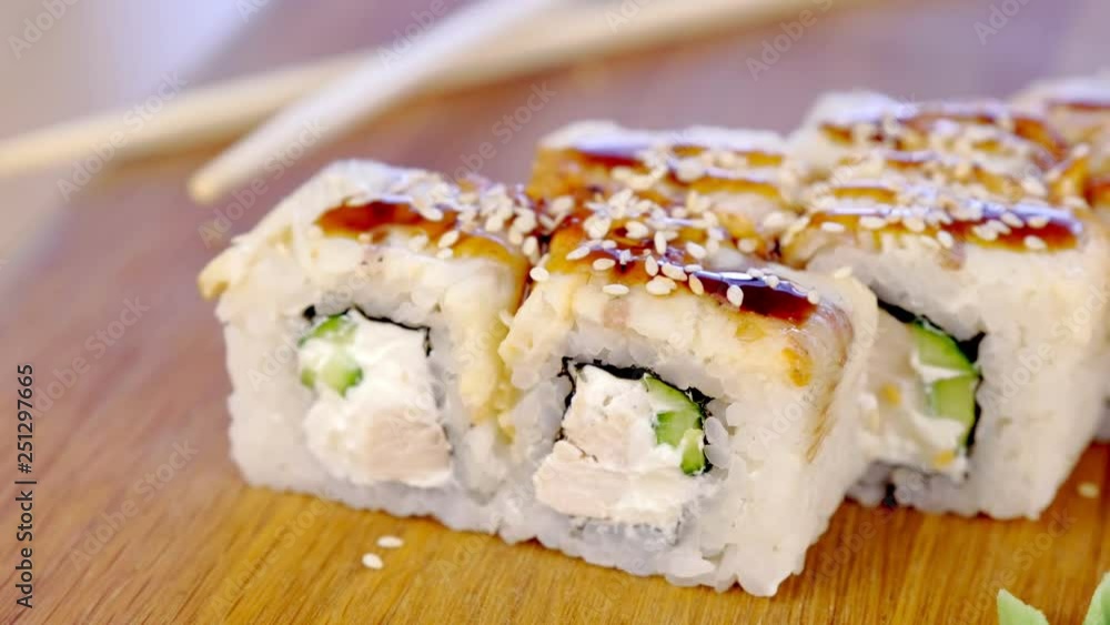 Rolls with fish and sesame seed on top served in wooden board with wasabi, ginger and soy sause. Rolls with fish and sesame seed on top served in wooden board with wasabi, ginger and soy sause.