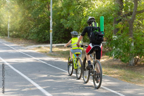 two cyclists, father and son ride a bike path in the park, family sport, lifestyle