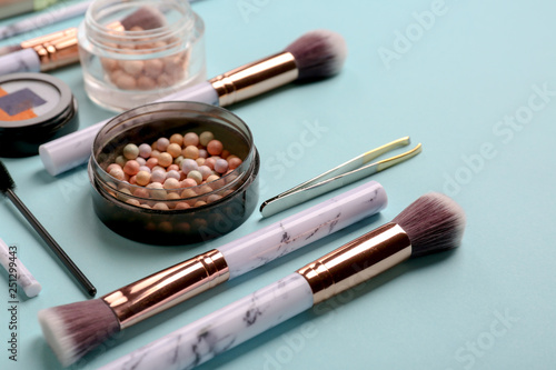 Professional makeup cosmetics with accessories on color background