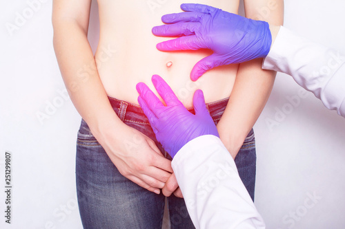 The doctor conducts a medical examination of the patient's girl whose abdominal pain, umbilical hernia of the abdomen