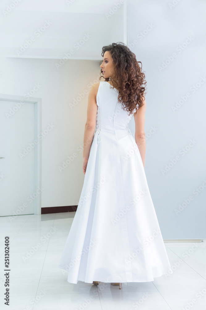 Beautiful young bride with curly hair in white wedding dress