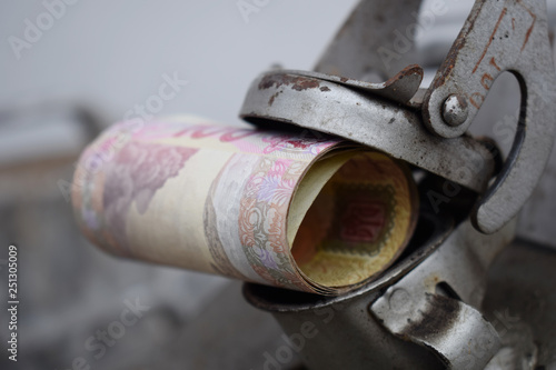 Metal barrel and Ukrainian money, the concept of the cost of gasoline, diesel, gas. Refilling the car. Roll of banknotes 100 hryvnia.