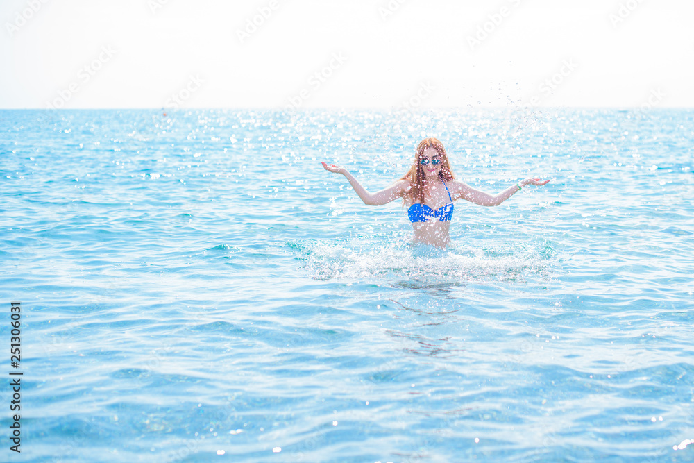 Redhead woman on a beach in vacation. Spring - summer time at trip. Girl in swimwear near sea 