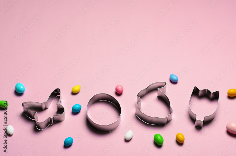 Fototapeta premium Easter Concept, Cookie Cutters and Chocolate Eggs on Pink Background