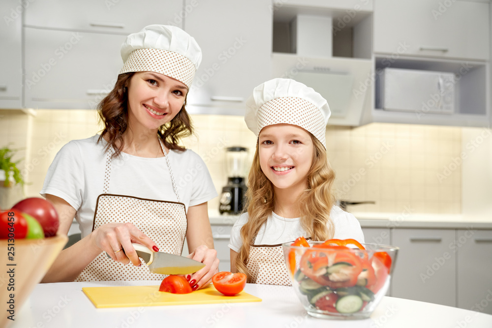 Mother and daughter posing in kitchen, cooking salad. Mother and daughter posing in kitchen, cooking salad.