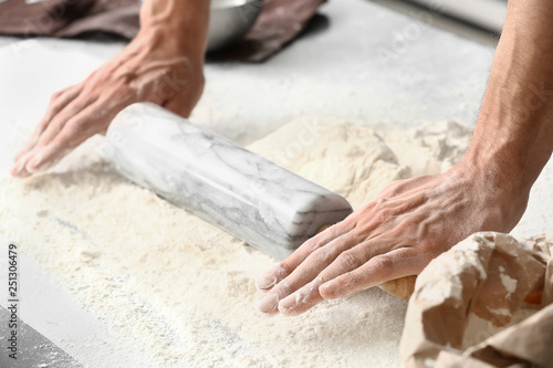Young man preparing dough for bread in kitchen, closeup © Pixel-Shot