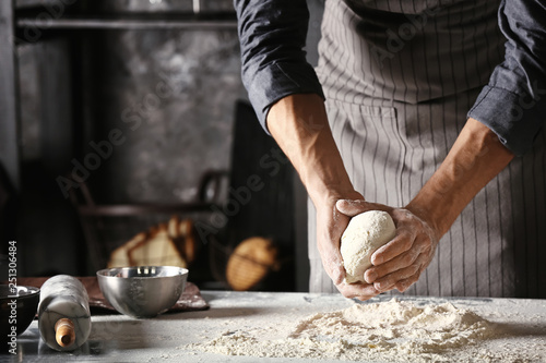 Fototapete Young man preparing dough for bread in kitchen