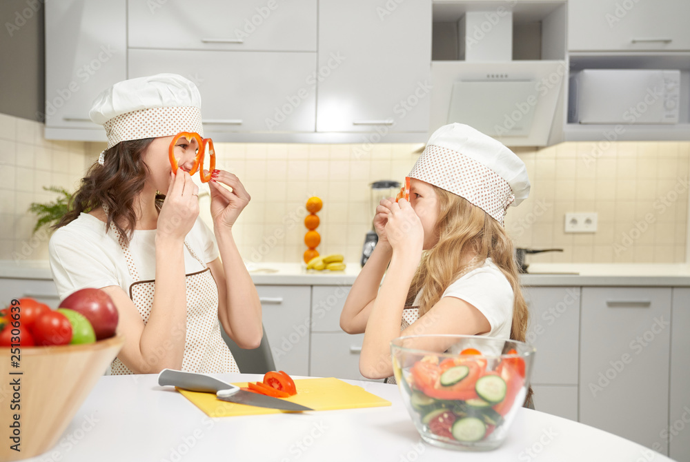 Funny mom and daughter holding pepper slices as glasses. Funny mom and daughter holding pepper slices as glasses.