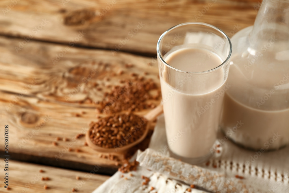 Glass and bottle of tasty buckwheat milk on wooden table Glass and bottle of tasty buckwheat milk on wooden table